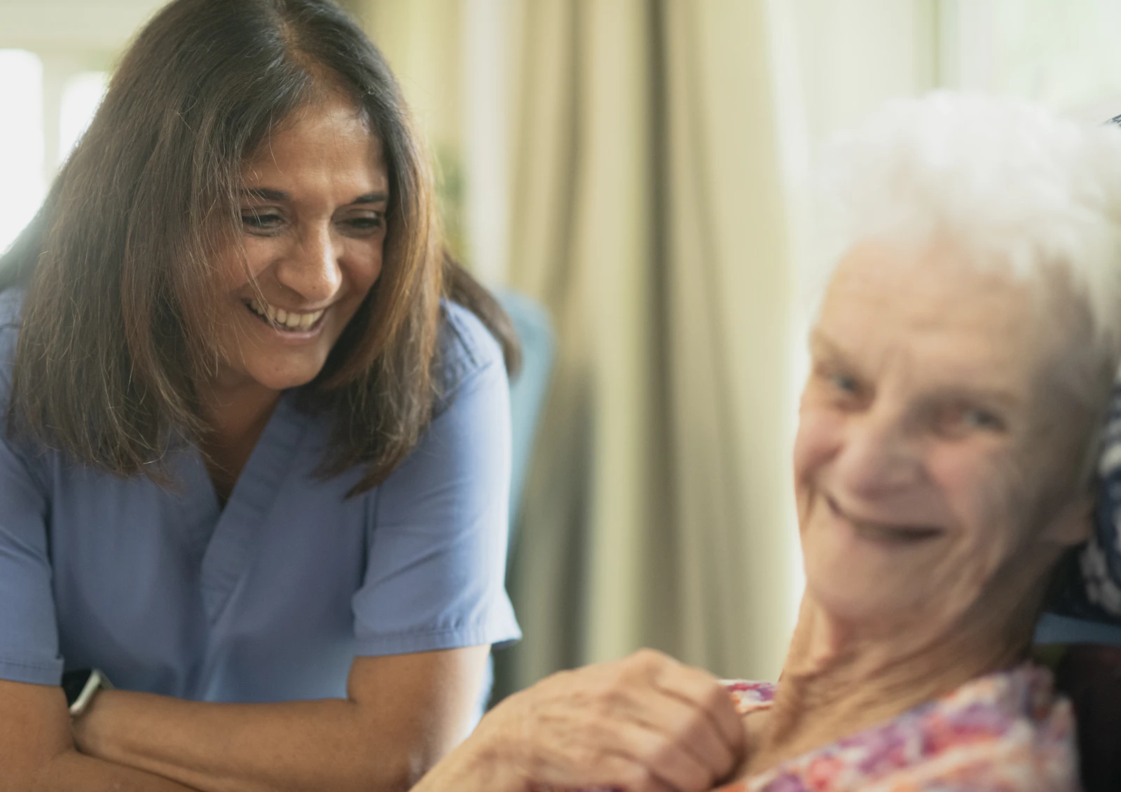Nurse smiling with elderly patient at home